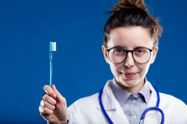 Dentist (blurred) holding a toothbrush (in focus) — Stock Photo, Image