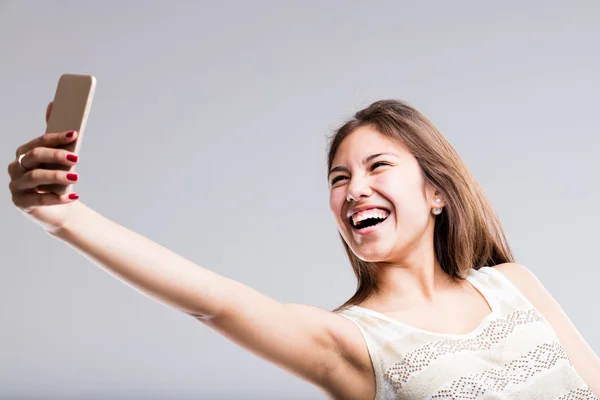 Женщина смеется над своим телефоном ради селфи — стоковое фото