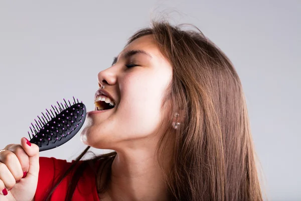 Leidenschaftliches Mädchen gibt vor, mit ihrer Haarbürste zu singen — Stockfoto