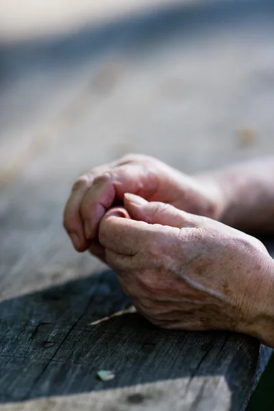 Faltige Hände einer alten Frau auf einem Tisch — Stockfoto