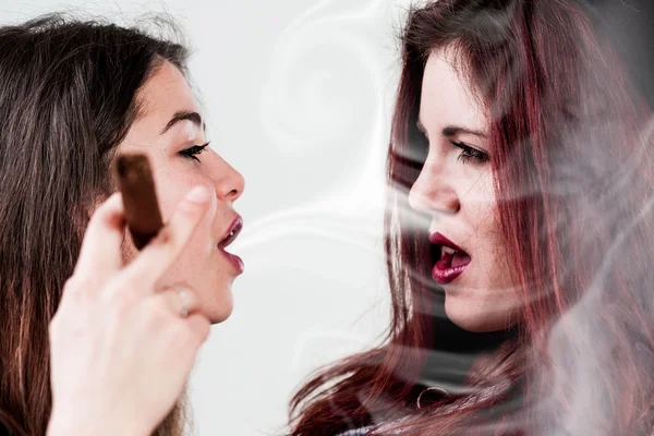 One woman blowing smoke on the other one 's face — стоковое фото