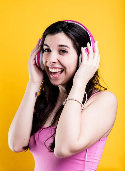 Kvinna lyssna på musik på sin rosa hörlurar — Stockfoto