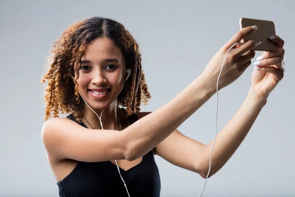 Ragazza dai capelli ricci ascoltare musica dal suo smartphone — Foto Stock