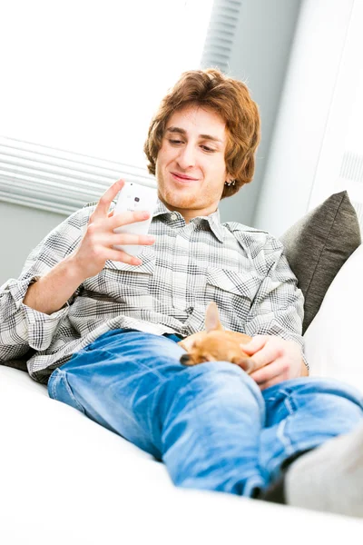 Hombre joven relajándose con su perro mascota y móvil — Foto de Stock