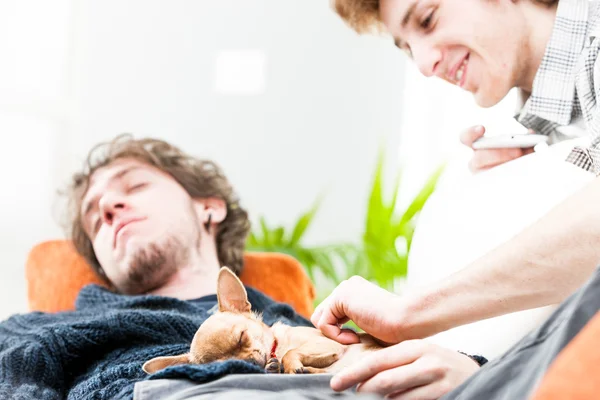 Joven hombre acariciando perro dormido con hermano — Foto de Stock