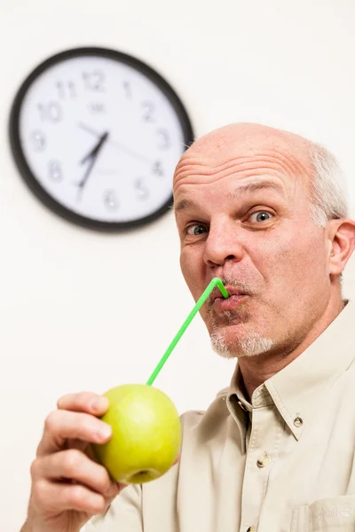Bärtiger älterer Mann schlürft Saft aus Apfel — Stockfoto