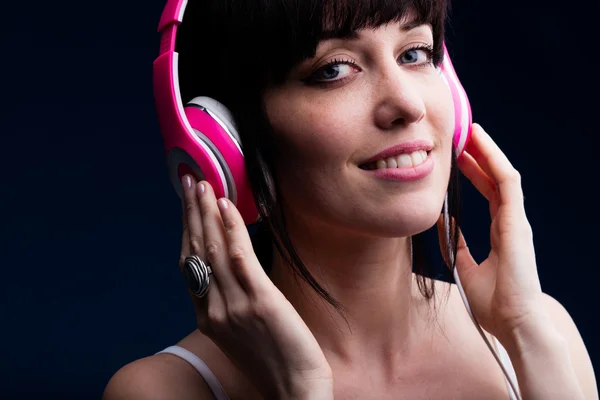 Sonriendo hembra adulta joven usando auriculares — Foto de Stock