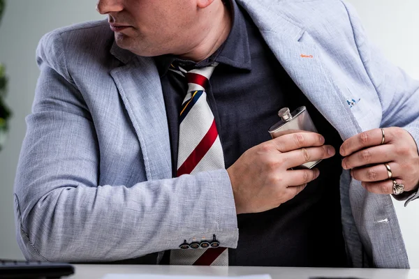 Офисный работник, прячущий фляжку во внутреннем кармане — стоковое фото