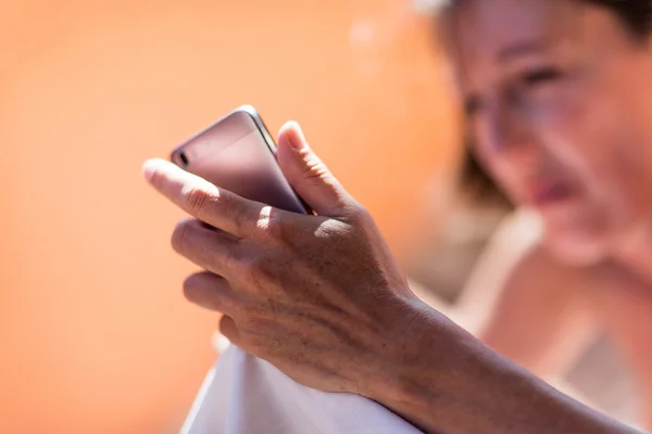 Verouderde huid op de hand van een vrouw met een mobiele telefoon — Stockfoto