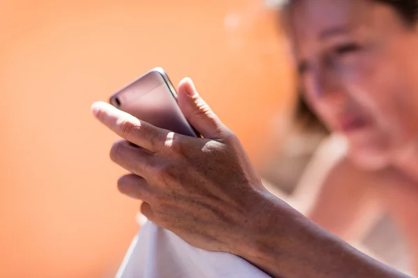 El bir cep telefonu tutan bir kadın, yaşlanmış cilt — Stok fotoğraf