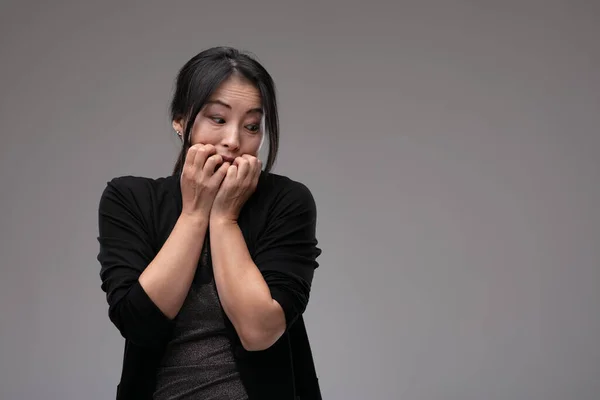 Страшная Беспокойная Азиатская Женщина Смотрит Сторону Грызет Ногти Трепете Сером — стоковое фото