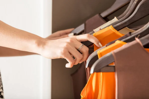 Kvinna Välja Orange Topp Från Plagg Hängande Skena Närbild Händerna — Stockfoto