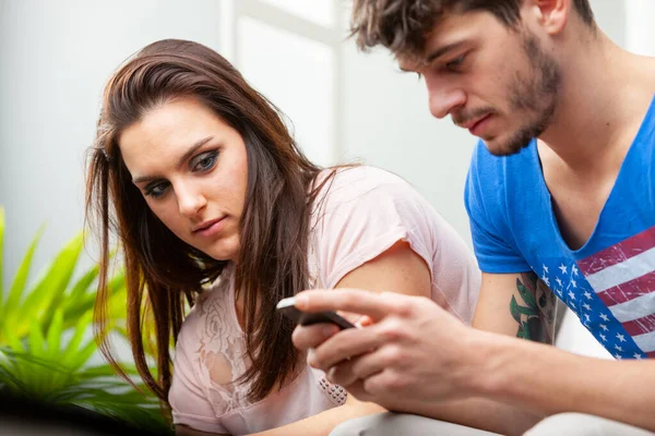 Mladá Žena Zamyšleně Sleduje Svého Přítele Pomocí Mobilního Telefonu Zblízka — Stock fotografie