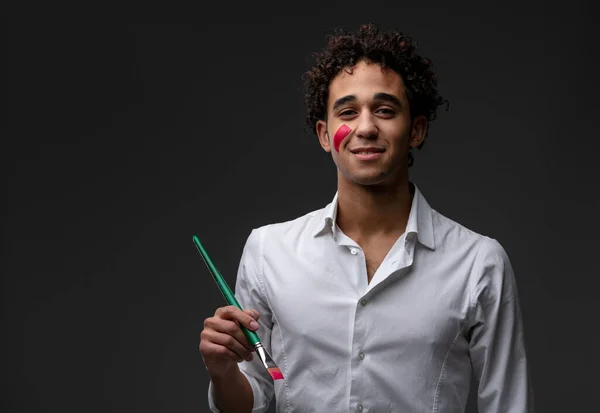 Smiling Young Curly Haired Artist Holding Paintbrush Colorful Daub Red — Stock Photo, Image
