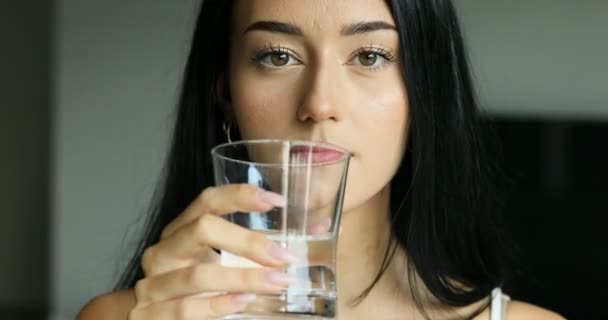 Νεαρή γυναίκα πίνει ένα ποτήρι νερό. — Αρχείο Βίντεο