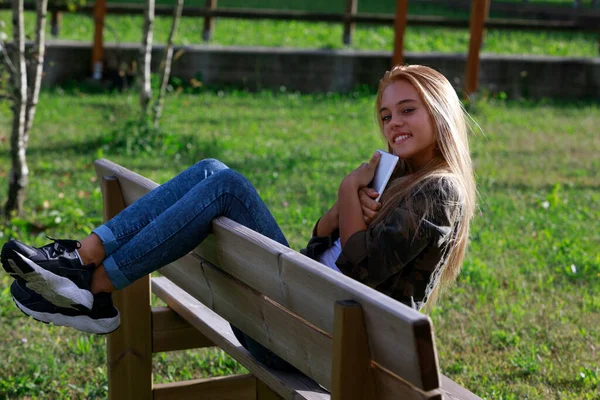 Счастливая Расслабленная Молодая Женщина Сидящая Скамейке Парке Закате Прижимая Мобильный — стоковое фото