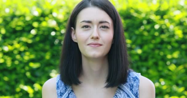 Face portrait of young woman in a garden expressing mixed positive and negative emotions — Stock Video