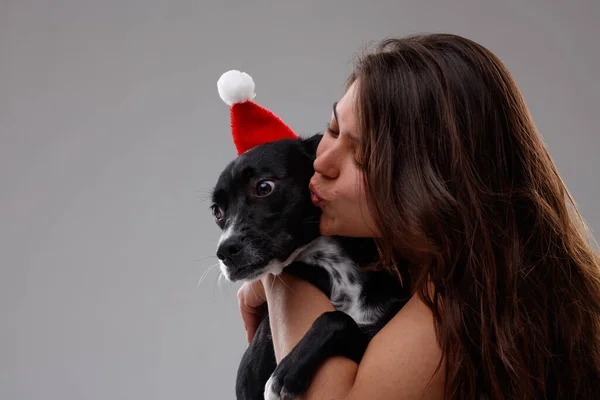 Young Woman Kissing Hugging Cute Little Dog Wearing Santa Hat Royalty Free Stock Images