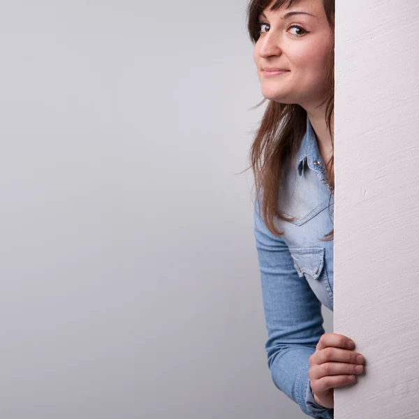 Trevlig tjej visar bakom den vita väggen — Stockfoto