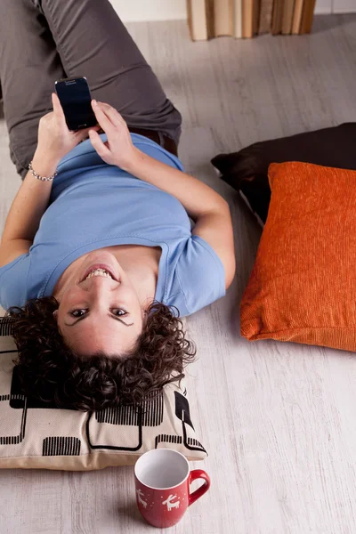 Chica sonriente y relajante mientras mensajería de texto —  Fotos de Stock