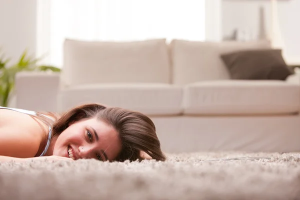 Menina feliz no tapete em sua sala de estar — Fotografia de Stock