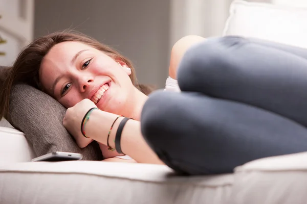 Молодая счастливая девушка, лежащая на диване — стоковое фото