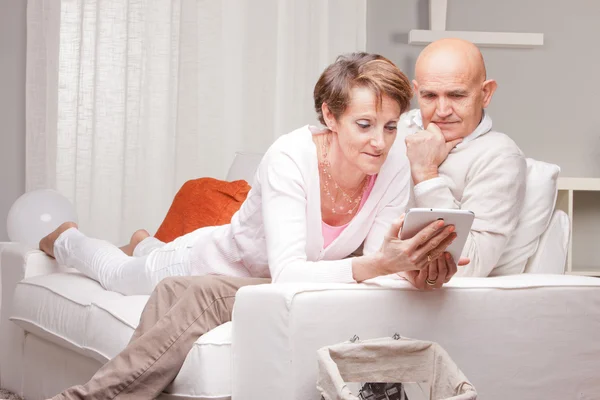 Pareja madura leyendo noticias en dispositivos digitales — Foto de Stock