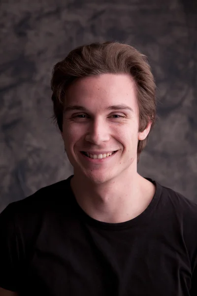 Smiling smart guy on a grunge black background — Stock Photo, Image