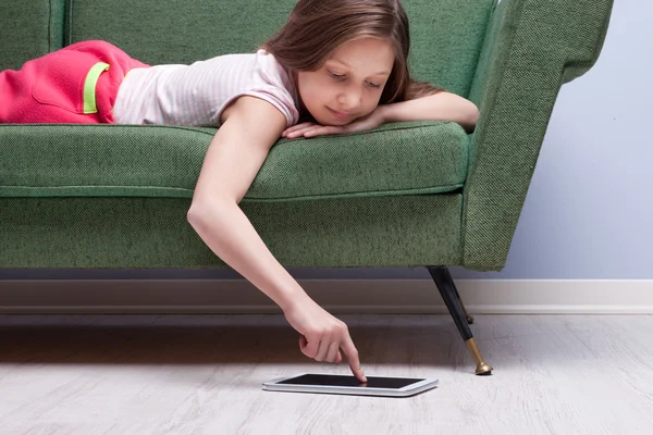 Menina usando um tablet relaxado em um sofá — Fotografia de Stock