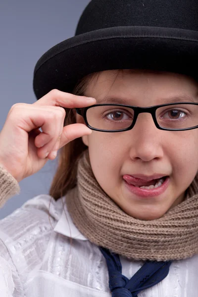 Flicka stickat ut hennes tunga med glasögon och hatt — Stockfoto