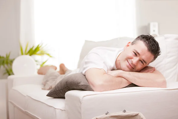 Man die lacht naar camera ontspannen in zijn woonkamer — Stockfoto