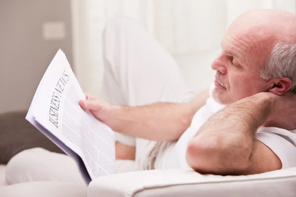 Uomo che legge un giornale su un divano — Foto Stock