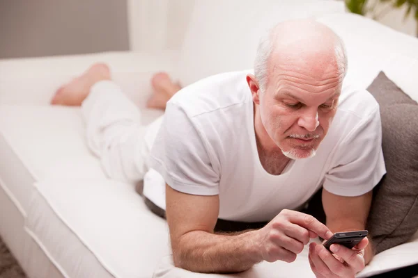 Mannen med en smartphone på en soffa — Stockfoto