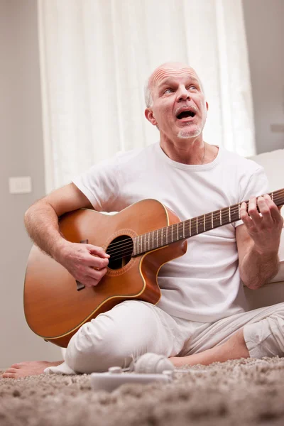 Зрелый мужчина играет на гитаре дома — стоковое фото