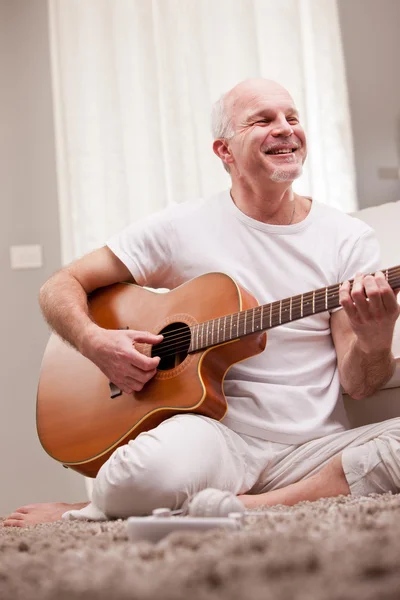 Dojrzały mężczyzna gra na gitarze w domu — Zdjęcie stockowe