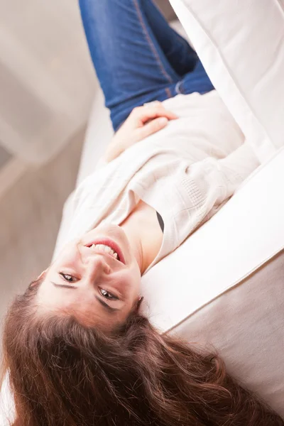 Hübsches Mädchen in blauen Jeans, das dich vom Sofa aus beobachtet — Stockfoto