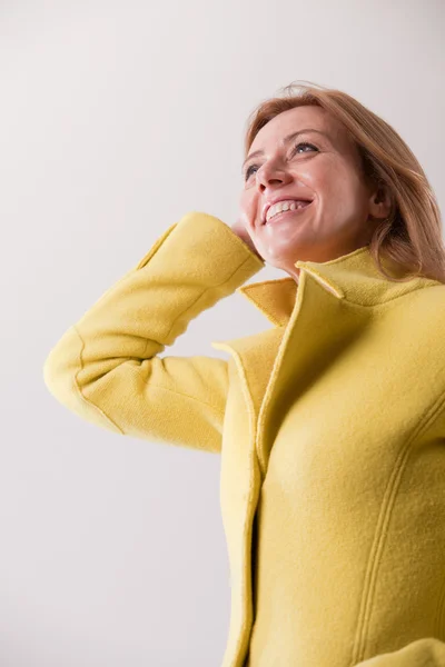 Happy mature blonde woman in yellow coat — Stock Photo, Image