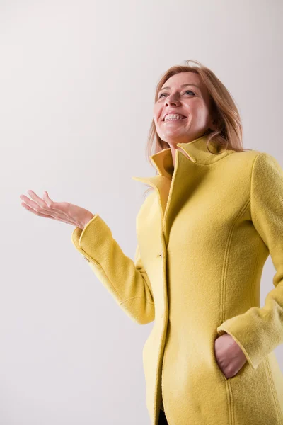 Happy mature blonde woman in yellow coat — Stock Photo, Image