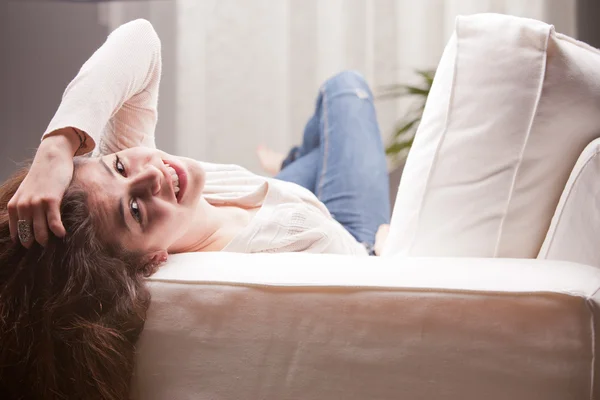 Young pretty girl lying on a couch and smiling — Stock Photo, Image