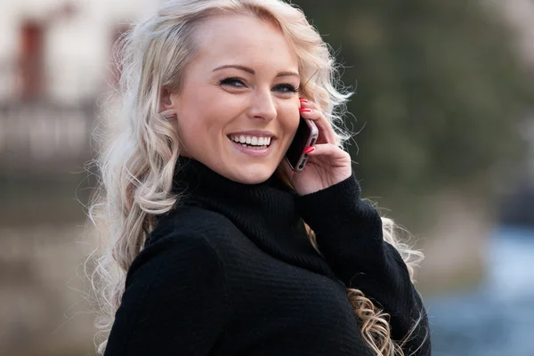 Blonde Frau spricht auf ihrem Handy lächelnd — Stockfoto