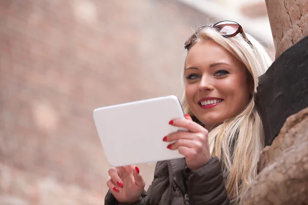 Blonda leende flicka med en tablett utomhus — Stockfoto