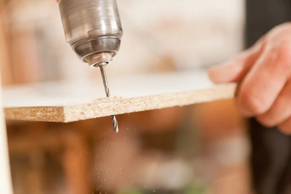 Broca aburrido un tablero de madera — Foto de Stock