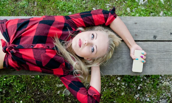 Donna sdraiata su panchina con telefono — Foto Stock