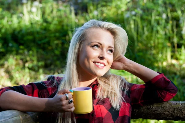 Ragazza bionda che beve dalla tazza gialla — Foto Stock