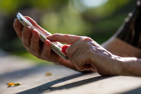 Dedo da mão envelhecida tocando um telefone celular — Fotografia de Stock