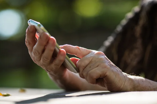 Палец пожилой руки, касающийся мобильного телефона — стоковое фото