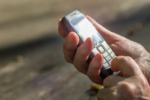 Finger der betagten Hand berührt ein Mobiltelefon — Stockfoto