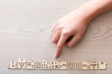 hand pointing out a house among the others mini figures in a mic clipart