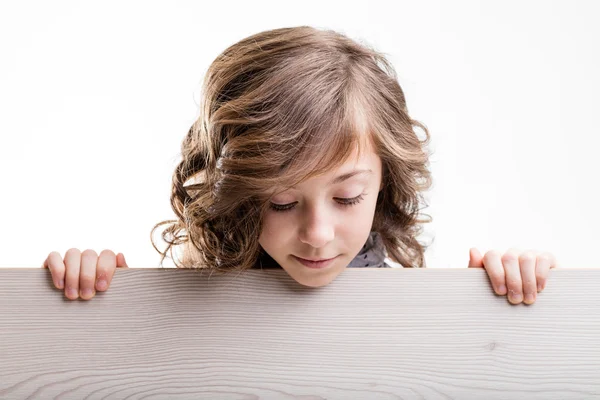 Niña pequeña que aparece detrás de un tablero y mirando hacia abajo —  Fotos de Stock