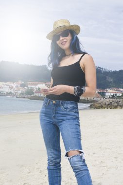 Sahilde cep telefonu olan bir kadın.